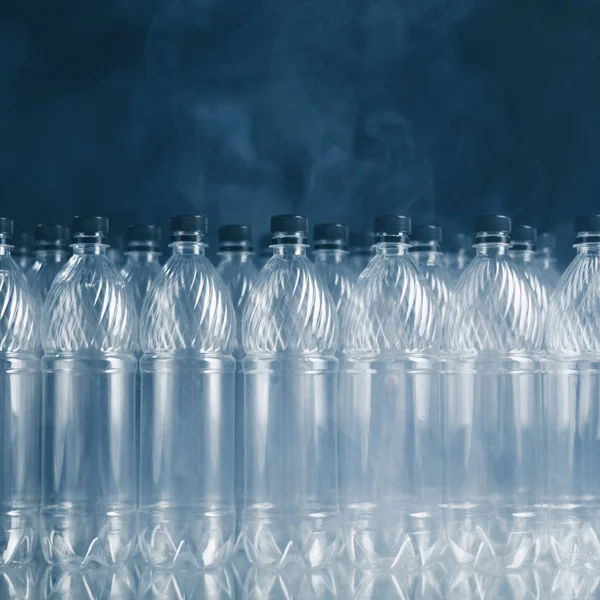 Tomma plastflaskor på svart bakgrund med rök, förorenings koncept — Stockfoto
