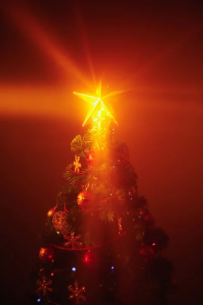 Weihnachtsbaum mit festlichen Lichtern, orangefarbener Hintergrund mit Nebel — Stockfoto