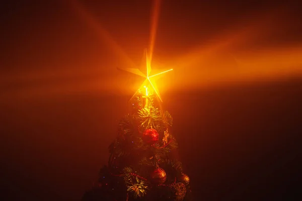 Kerstboom glanzende ster lichten, oranje achtergrond met mist — Stockfoto