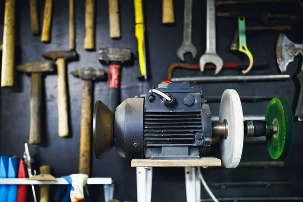 Slijpmachine in oude garage, muur met roestige hamers achtergrond — Stockfoto