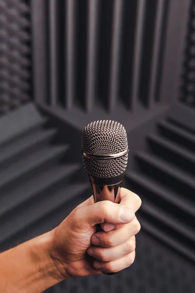 Micrófono dorado en la mano, fondo gris con espuma acústica en el estudio —  Fotos de Stock