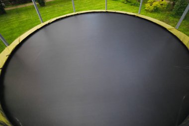 trampoline with big round mat on green lawn clipart