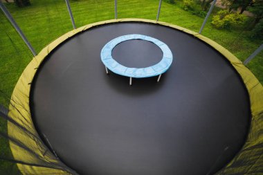 small trampoline on big one with round mat, size comparison, green lawn background clipart