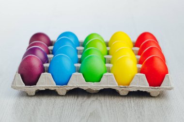 Paskalya bayramı çok renkli yumurta kutusu, açık gri ahşap arka plan, yakın çekim manzarası.