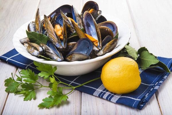 Варёные мидии с лимоном и петрушкой на столе
