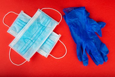 Kırmızı zemin üzerinde 19 koronavirüsü korumak için cerrahi maske ve eldivenler.