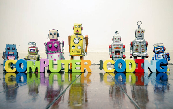 слова COMPUTER CODING с деревянными буквами и ретро-игрушечными роботами на старом деревянном полу с надписью
