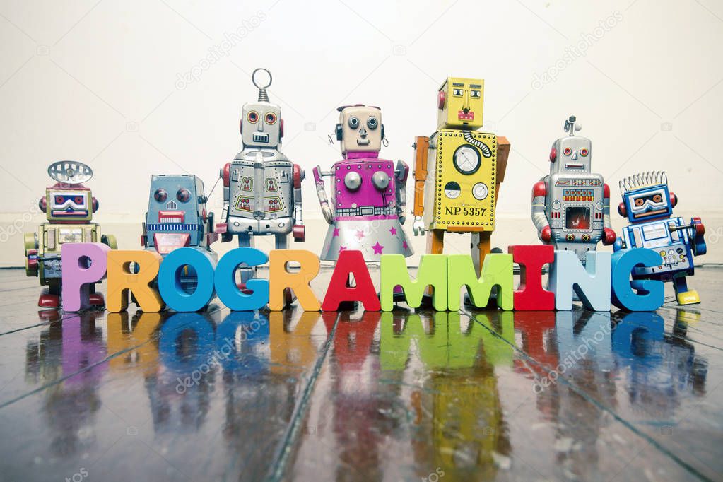 the word  PROGRAMMING with wooden letters and retro toy robots  on an old wooden floor with reflection