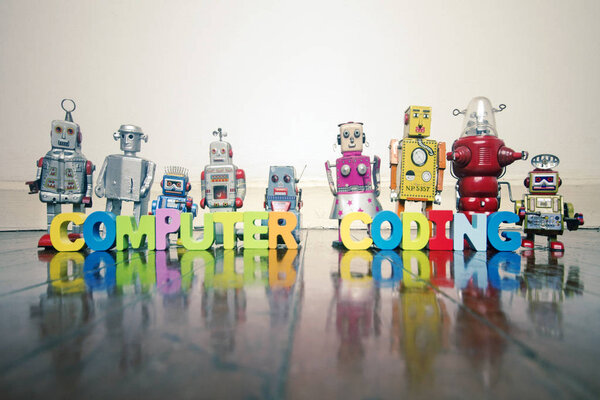 КОМПЬЮТЕР Кодирование деревянных букв и игрушек ретро-роботов на деревянном полу с отражением
