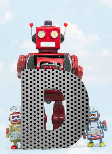 Retro robots houden een grote metalen letter D met blauwe hemel — Stockfoto