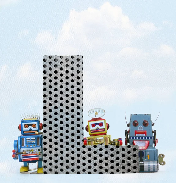 Retro robôs segurando uma grande letra de metal L com céu azul — Fotografia de Stock