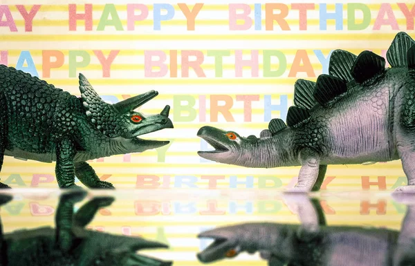Dinossauros de brinquedo com fundo feliz aniversário — Fotografia de Stock