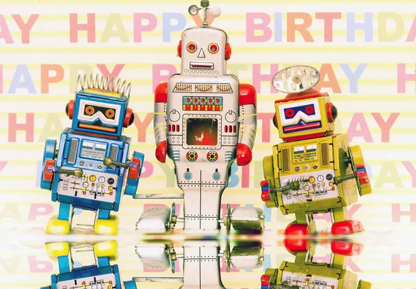 Three retro bots with HAPPY BIRTHDay background — стоковое фото