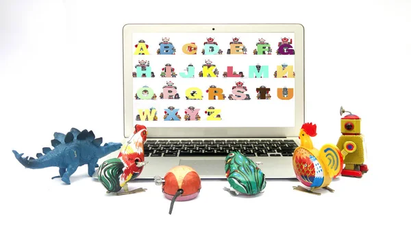 Жестяные игрушки опираются на алфавит на ноутбуке — стоковое фото