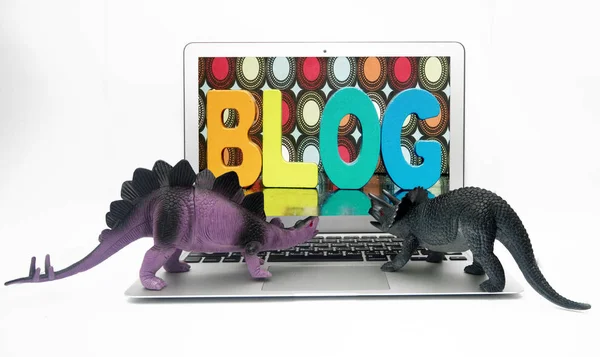 Dinosaur toys check ther blog on a laptop — Stock Photo, Image