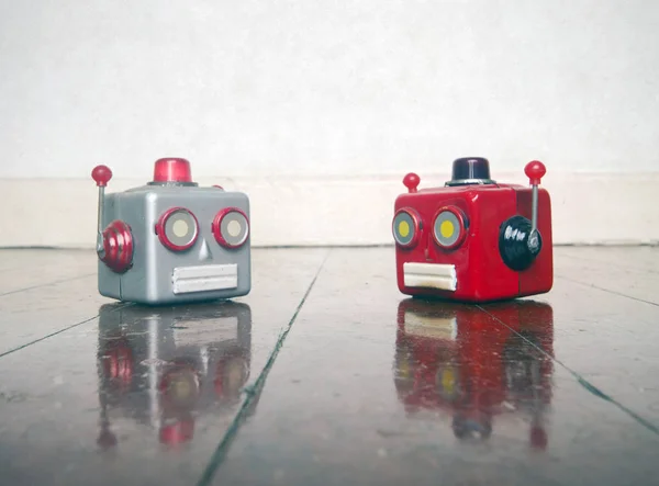 Deux têtes de robots métalliques bavardant sur un plancher en bois — Photo