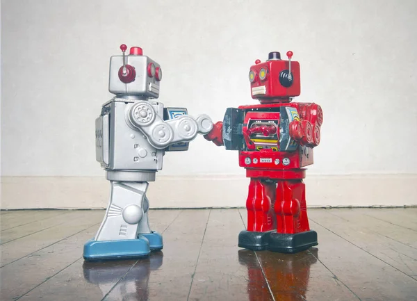 Två retro robot leksaker skaka hand — Stockfoto