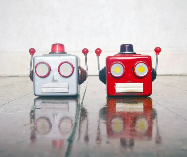 Two metal robot heads chatting on a wooden floor — Stock Photo, Image