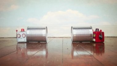 Teneke telefonlar üzerinde konuşan iki eski robot kafası.