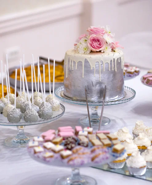 Torta nuziale e vario dolce cibo su un tavolo — Foto Stock