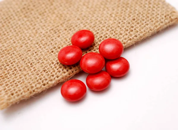Pil merah multivitamin pada latar belakang tas jute — Stok Foto