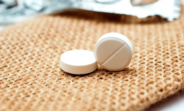 Λευκό παυσίπονο χάπια σε φόντο τσάντα μικρή Γιούτα — Φωτογραφία Αρχείου