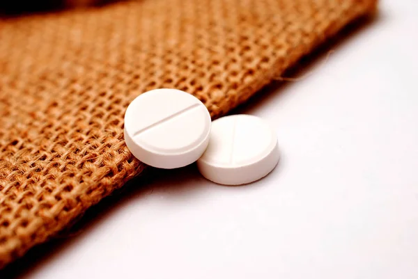 Pillole antidolorifici bianchi su un piccolo sfondo sacchetto di iuta — Foto Stock