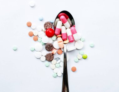 bir kaşık beyaz arka plan üzerinde çeşitli hap,,
