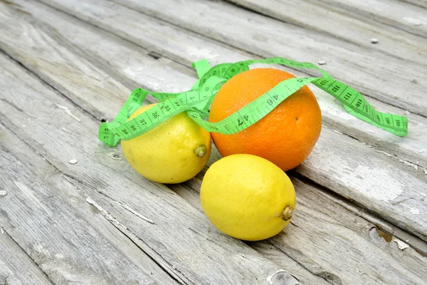 Zitronen, Orange und Maßband auf Holzgrund — Stockfoto