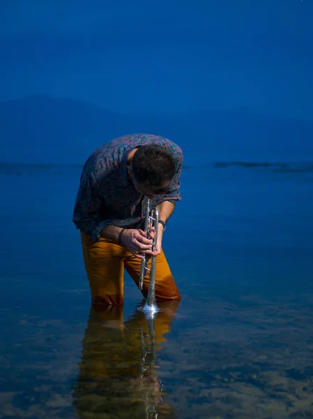 portrait of a trumpeter musician barefoot in a water of lake prespa in macedonia