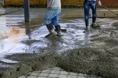 Yeni bir binanın betonunu döşeyen işçiler.