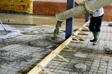 Yeni bir binanın betonunu döşeyen işçiler.