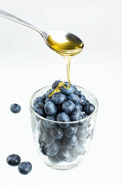 Ekşi bardakta taze yabanmersini ve bir kaşık bal.