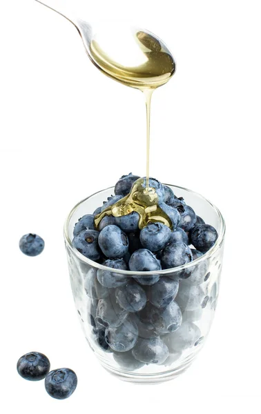 Ekşi bardakta taze yabanmersini ve bir kaşık bal.