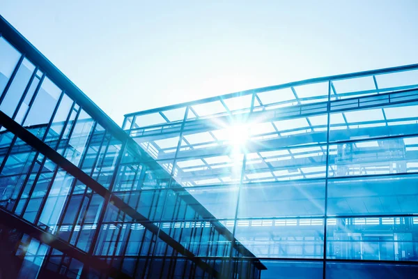 Mavi gökyüzünde güneş ışınları ile gökdelen cam cepheler. Modern binalar
