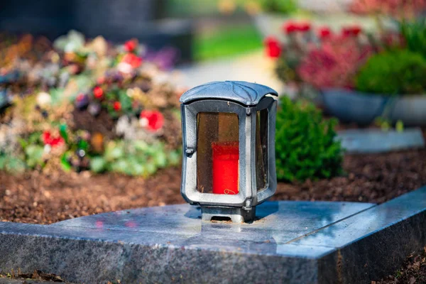 Une bougie rouge sur les pierres tombales avec des fleurs — Photo