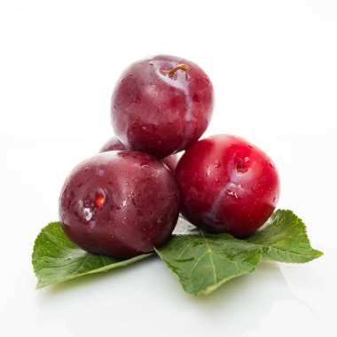 Beyaz arkaplanda yeşil yapraklı kırmızı erik