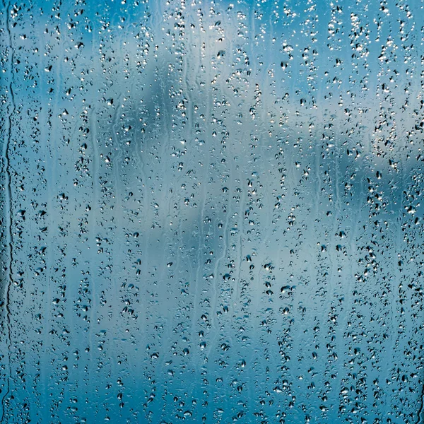 Obfite krople deszczu na niebieskie okno — Zdjęcie stockowe