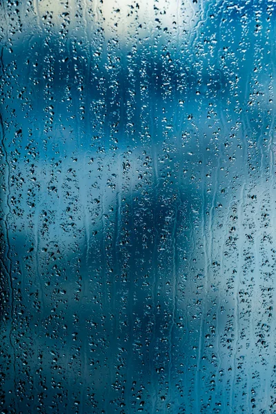 Gotas de chuva na janela fundo azul — Fotografia de Stock