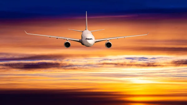 夕阳西下在云上飞行的商业客机 — 图库照片