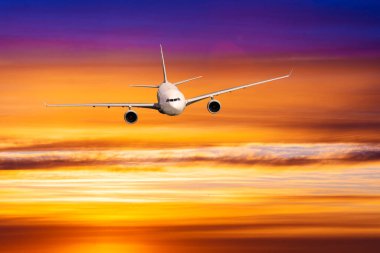 Günbatımında bulutların üzerinde uçan ticari uçaklar. 