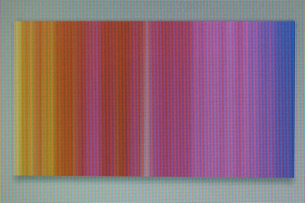 A macro photo of a chaotic colored striped noise on the monitor screen. A well-seen pixel structure