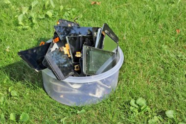 Plastik kutu yalan yeşil çim çimen üzerinde kırık ve kırık hücresel telephons yığını. Çevre copncept modern teknolojiler kirleten. 