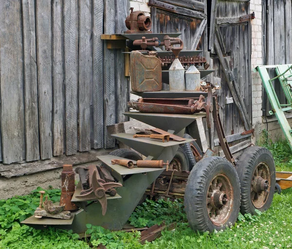 生锈的老式小型拖拉机晶石零件和 Retrol 机械在农村棚子附近 金属设备是在百年前制造的 批量生产 — 图库照片