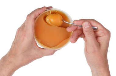 Yaşlı bir adam arı altın rengi bal bir kaşık ile plastik bir kaseden alır. Beyaz stüdyo portre vurdu izole