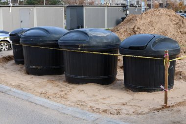 Şehir sokakta yeni modern siyah plastik kaplar ev çöp toplanması için yükleyin