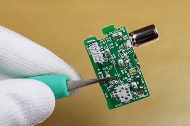 Bir teknisyen mobil ses cihazlar için bir mini fm radyo alıcısı kalitesini kontrol eder. Seri üretim. Modern teknoloji makro kavramı.