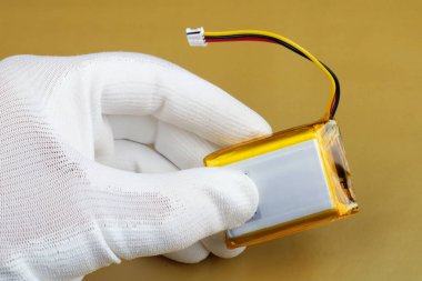 Bir teknisyen için hareket eden aygıt yeni bir lityum pil kalitesini kontrol eder. Seri üretim. Modern teknoloji makro kavramı.