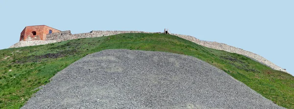 Le rovine di un antico muro della fortezza su una collina erbosa contro t — Foto Stock