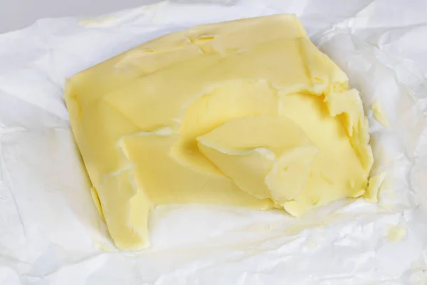 Ancien morceau de beurre de vache usagé sur l'emballage en papier d'aluminium — Photo